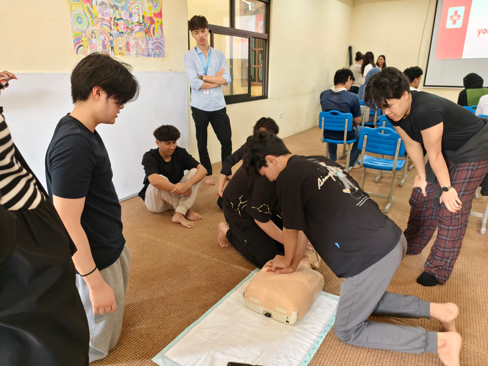 Beatkeepers workshop participants learning together as a student practises chest compressions on a CPR manikin