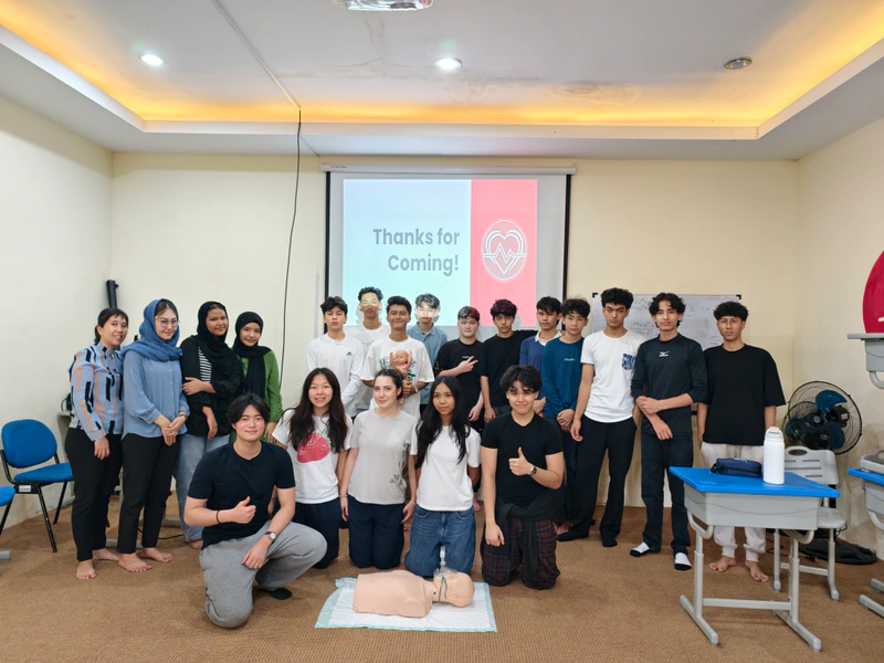 Workshop participants and coaches gather for a group photo in their classroom