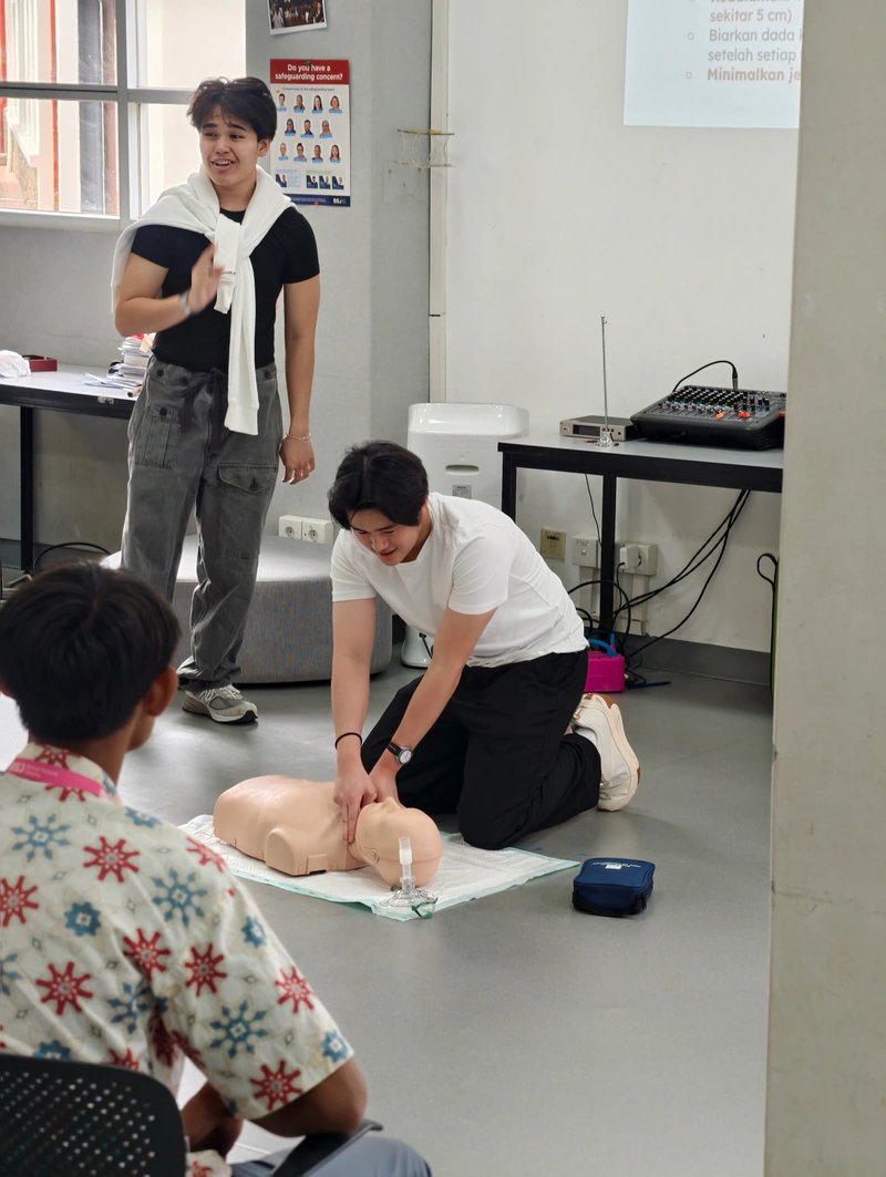 Two workshop coaches demonstrate chest compressions to a seated participant